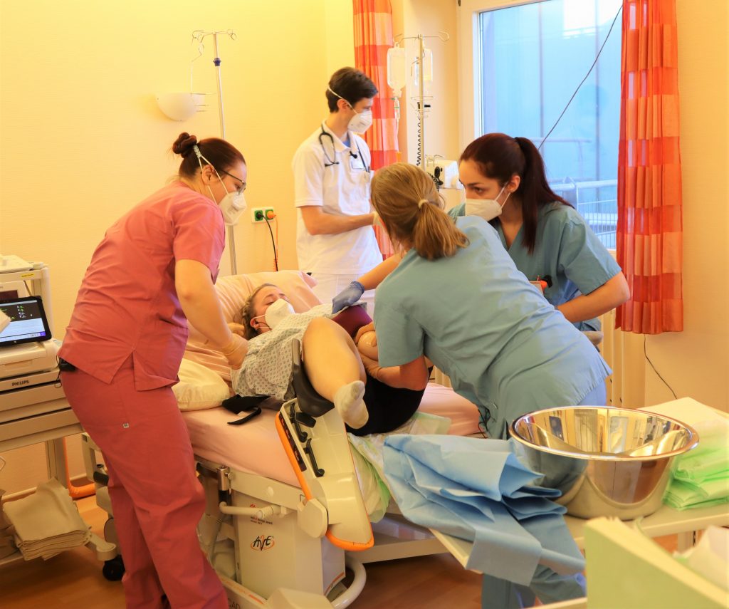im Kreißsaal findet ein Simulationstraining statt, wobei Hebammen und Ärzte anwesend sind. Geburtshilfe und Gynäkologie Klinikum Landsberg.