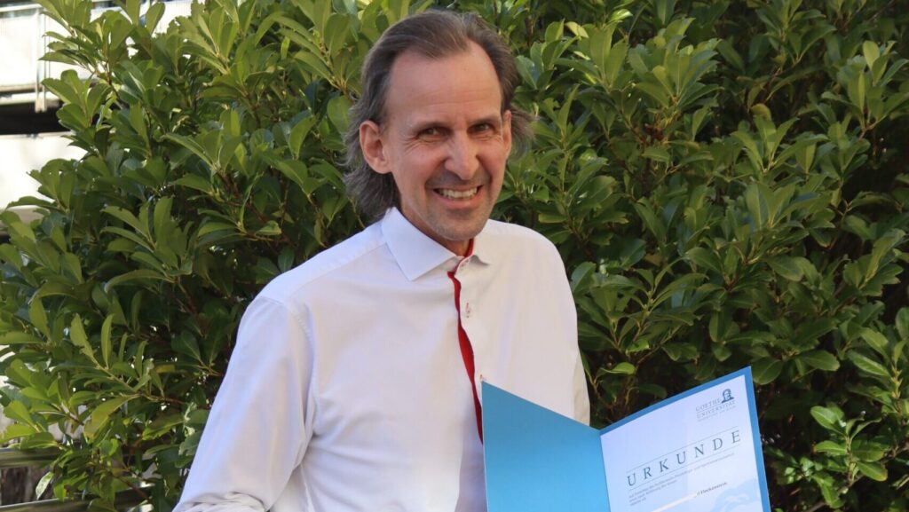 Professor Fleckenstein hält strahlend seine Urkunde, in welcher er vor kurzem zum Professor ernannt wurde, in der Hand. Klinikum Landsberg.