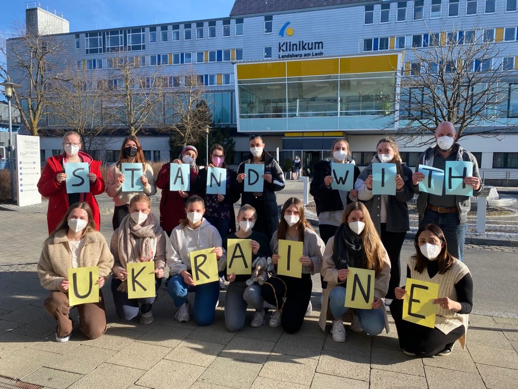 Schüler und Schülerinnen der Berufsfachschule für Pflege halten Buchstaben in den Händen: "Stand with Ukraine." Eine tolle Spendenaktion: in Zusammenarbeit mit humedica e.V. werden die Spenden an die Betroffenen weitergeleitet.